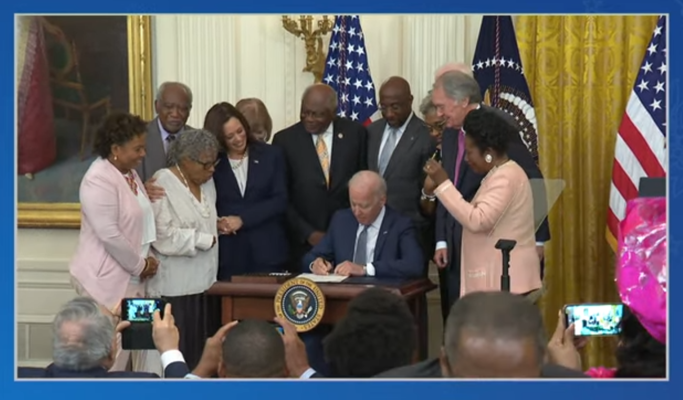 Kamala Harris with her arm around Opal Lee watches Joe Biden sign the law declaring Juneteenth a federal holiday